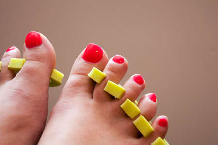 womans feet with fresh red nail polish and toe separators to help dry without smudgingの写真素材