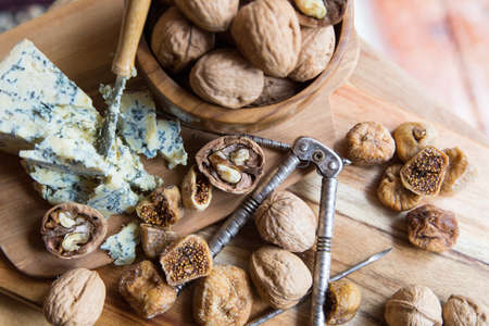 dried figs, walnuts and blue cheese on a wooden board for a gourmet snackの写真素材
