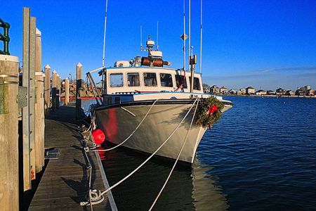 Christmas lobster Boat: this lobster boat sits tied at the dock waiting for spring and the fishing season still wearing it's Christmas wreath.の写真素材
