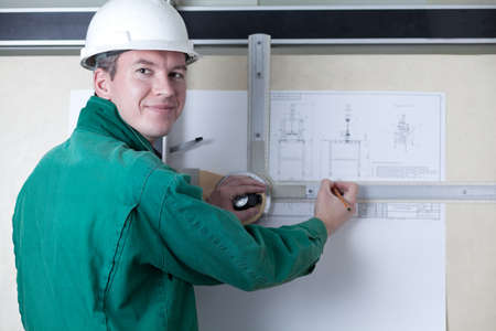 an engineer standing by the adjustable drawing board with a pencilの写真素材