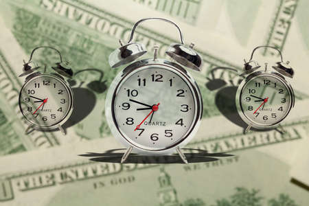 Time is money. Alarm clock on money backgroundの写真素材