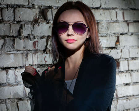 Beautiful young woman wearing sun glasses. Harsh dramatic lighting.の写真素材