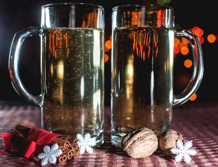New Year's eve. Funny image of two beer glasses of champagne, snowflakes, cinnamon and walnuts on the background of lights bokeh. Low key. Selective focus.の写真素材
