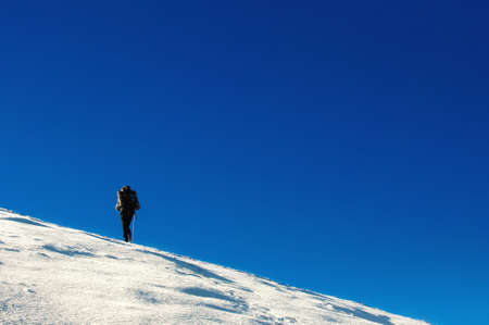 Hiker climbs to the top of Chatyr Dag mountain in the Crimean mountains. Graphically image with clear deep blue sky and white showy slope.の写真素材