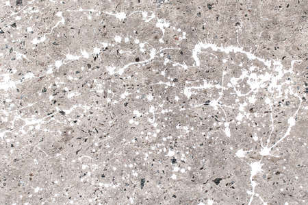 Texture of stained gray concrete with spots of white paint close up