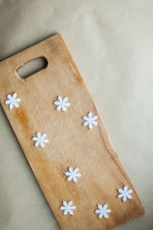 Snowflakes border on wooden background flat lay. Winter holidays funny kitchen concept. Cutting...