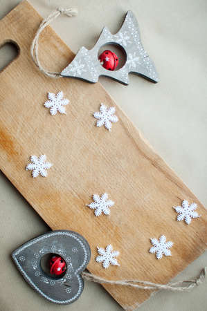 Snowflakes border on wooden background flat lay. Winter holidays funny kitchen concept. Cutting board background with white snowflakes and rustic wooden Christmas toys, top view.の写真素材