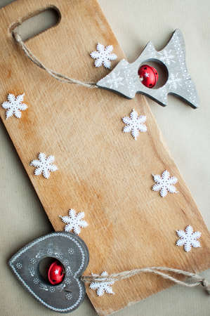 Snowflakes border on wooden background flat lay. Winter holidays funny kitchen concept. Cutting board background with white snowflakes and rustic wooden Christmas toys, top view.の写真素材