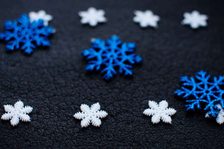 White and blue Christmas snowflakes decoration on black textured background close up. Winter wallpaper. Selective focus.の写真素材