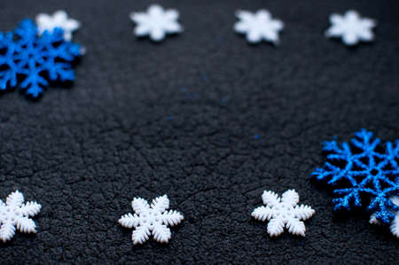 White and blue Christmas snowflakes decoration on black textured background close up. Winter wallpaper. Selective focus.の写真素材