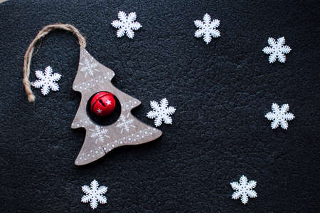 Little white Christmas snowflakes decoration and wooden Christmas toy on black textured background....