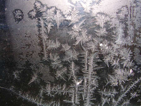 Ice pattern and sunlight on winter glass. Natural frost floral pattern with abstract lines, stems and snowflakes on the glass close up.の写真素材