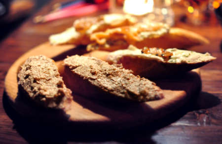 Toasted bread with pate, salmon and vegetables on wooden cutting board in a restaurant. Five different sandwiches, variety of flavors. Low key, selective focus.の写真素材