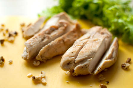 Ruddy chicken breasts with leaf salad and crushed walnut on yellow cutting board. Ingredients for salad preparation.の写真素材