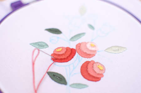Embroidery with floral motif framed in a hoop. Work in process. Close up, soft selective focus.の写真素材