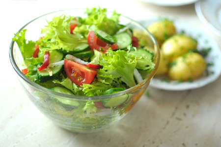 fresh vegetable salad with tomato, cucumber and salad frisee in glass bowl. Process of cooking. Close up, selective focus.の写真素材