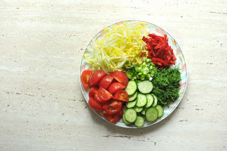 Mix of fresh organic raw sliced vegetables on the white plate on the wooden table. Top view, flat lay.の写真素材