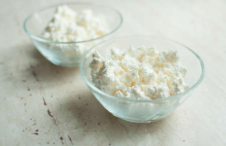 Two bowls of cottage cheese on the wooden table. Close-up, selective focus.の写真素材