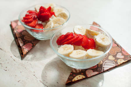 Two bowls of cottage cheese with strawberry and banana. Close-up, selective focus.の写真素材