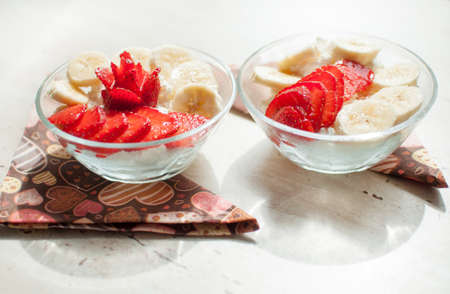 Two bowls of cottage cheese with strawberry and banana. Close-up, selective focus.の写真素材