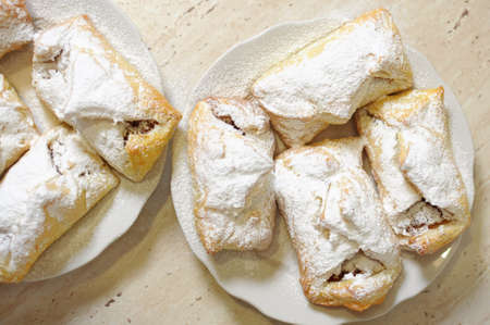 puffs with apple jam and sugar powder on two white plates close upの写真素材