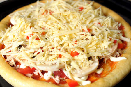 Homemade pizza, process of cooking. Layer of grated cheese close upの写真素材