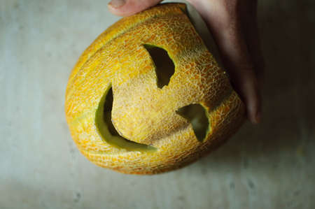 Unusual Halloween melon, cutting process, knife and male hands. Selective focus and bokeh.の写真素材