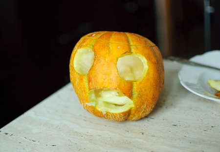 Unusual Halloween melon, cutting process, knife and male hands. Selective focus and bokeh.の写真素材