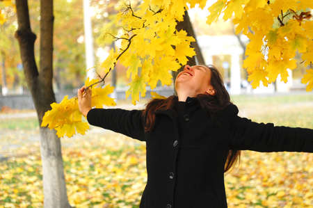 A funny young attractive girl has fun and fooling around in an autumn park. Cheerful emotions, autumn mood.の写真素材