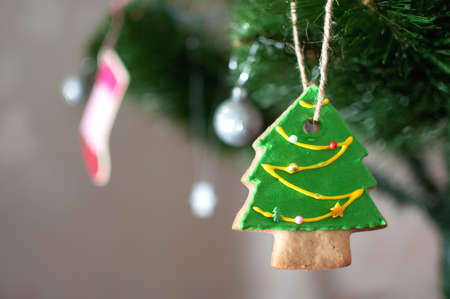 Cookie in the form of a Christmas tree is hanging on a branch of Christmas tree. Selective focus, bokeh. Holiday background or image.の写真素材
