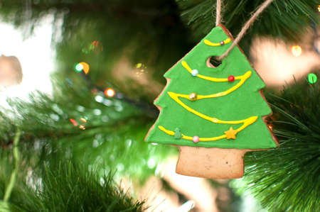 Cookie in the form of a Christmas tree is hanging on a branch of Christmas tree. Selective focus,...