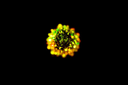 A small lighting yellow Christmas tree on the black background. Selective focus, top view. Abstract colorful Christmas background.の写真素材