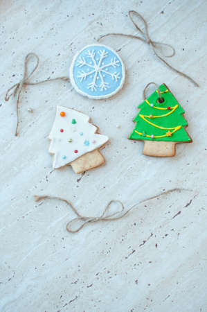 Two gingerbread cookies in the shape of the green and white Christmas tree and one cookie in the...