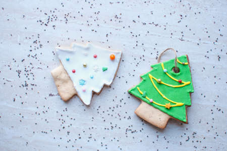 Two gingerbread cookies in the shape of the green and white Christmas tree on the background of a wooden table and scattered chia seeds. Top view, flat lay.の写真素材