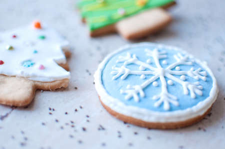 Two gingerbread cookies in the shape of the Christmas trees and one cookie in the shape of a round blue snowflake on a wooden table and scattered chia seeds. Top view, cropped image, selective focus.の写真素材