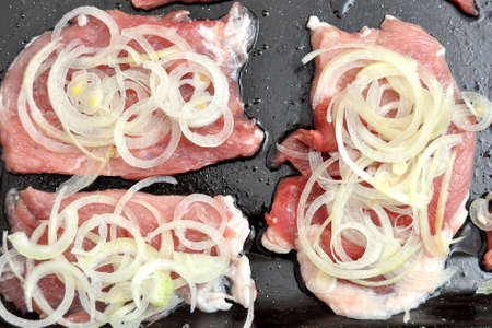 Raw pork chops on a black baking tray. Process of cooking step by step. Top view, flat lay.の写真素材