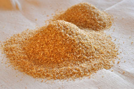 Two piles of wheat grain on the background of sackcloth close-up.
