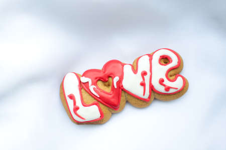 Letter cookies for Valentines day or for a wedding day on the background of white lightweight fabric.の写真素材