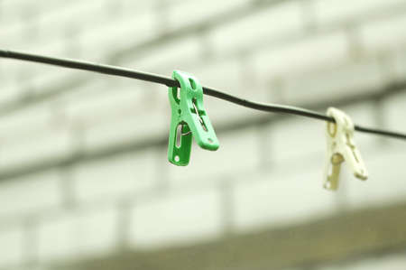 Two clothespins on a rope on the background of a brick wall of house. Selective focusの写真素材