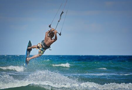 man kitesurfer athlete jumping while performing kite-surfing jump kite-boarding school kite spotの写真素材