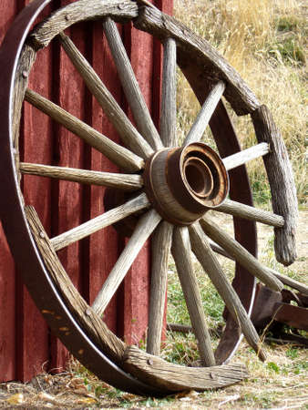 Wooden wheel wagon leaning against red barnの写真素材