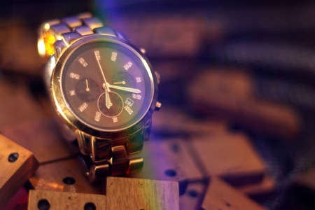 Luxurious gold watch on top of domino pieces and dark background with a light refractionの写真素材
