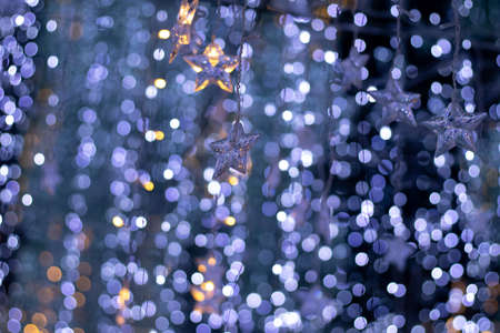 Rain of bokeh lights and star shaped ornaments with a dark bluish background