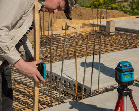Men is measuring height level of the building foundation with special equipment