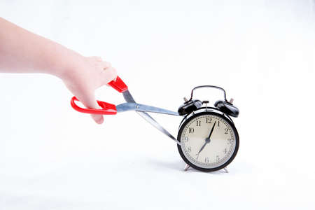 Hand cuts the alarm clock with scissorsの写真素材