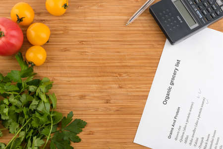 Purchase list surrounded by a fresh tomatoes and calculator on old wooden tableの写真素材