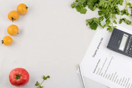 Purchase list surrounded by a fresh tomatoes and calculator on white backgroundの写真素材