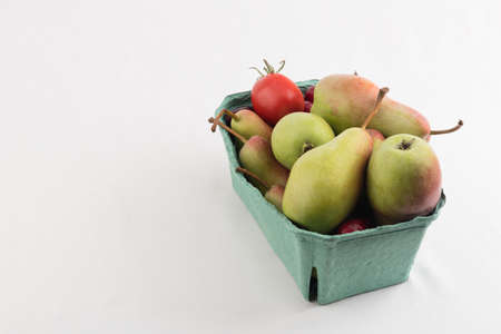 fresh juicy pears and tomatoes in a carton box on white backgroundの写真素材