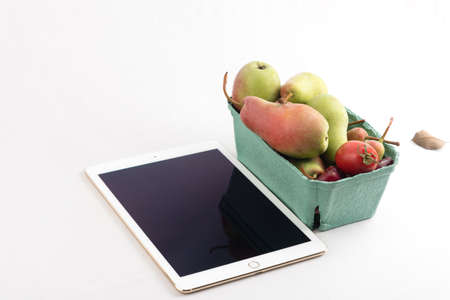 Fresh pears and tomatoes in a carton box and tablet pc on white backgroundの写真素材