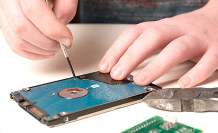 Hard drive repair with screwdriver by human handsの写真素材